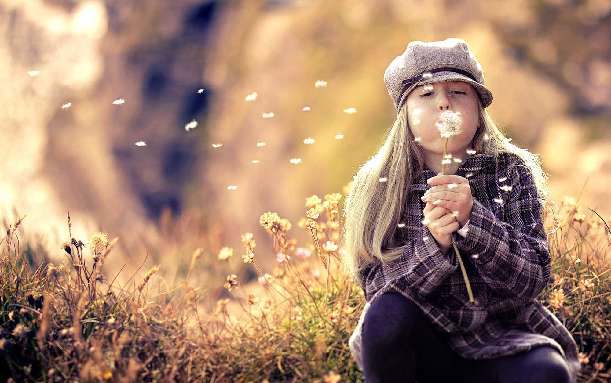 Bambina che soffia su un soffione